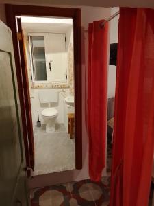 ein Badezimmer mit einem WC und einem roten Duschvorhang in der Unterkunft Il trullo della nonna in Martina Franca + 17 Fotos