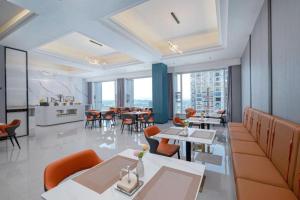 une salle à manger avec tables, chaises et fenêtres dans l'établissement Borrman Hotel Yongzhou Lingling Ancient Town Government, à Yongzhou