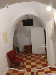 ein Zimmer mit kariertem Boden, einem Stuhl und einem Fernseher in der Unterkunft Il trullo della nonna in Martina Franca