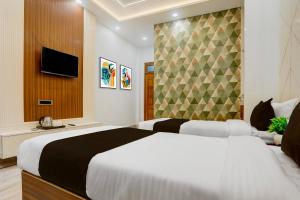 a hotel room with two beds and a television at Super Townhouse Vishwanath Temple Varanasi in Varanasi