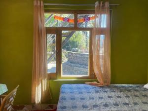 - une chambre dotée d'une fenêtre avec des rideaux et un lit dans l'établissement Munsiyari ECo Homestay and dormatory, à Munsyari