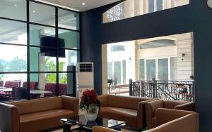 - un salon avec des canapés, une table et des fenêtres dans l'établissement The Crew Hotel Kualanamu International Airport, à Kampungbesar