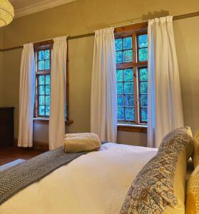 a bedroom with a large bed with two windows at Splash 9 in Trompsburg