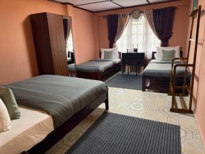 1 Schlafzimmer mit 2 Betten und einem Schreibtisch in einem Zimmer in der Unterkunft RUU Holiday Home in Nuwara Eliya