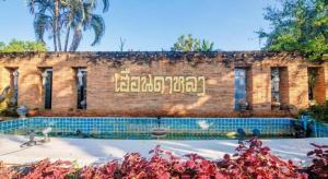 a brick building with a sign on the side of it at Huandalha Resort in Ban San Pa Sak