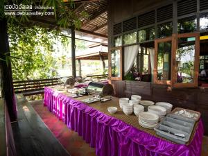 a table with a purple table cloth and white dishes at De Bua Valley in Ban Kom