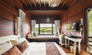 - une chambre avec un lit et une fenêtre avec un banc dans l'établissement The Blue Sky Resort@ Koh Payam, à Ko Phayam