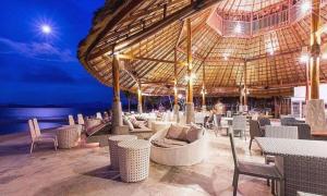 un restaurant avec des chaises, des tables et un grand parasol dans l'établissement The Blue Sky Resort@ Koh Payam, à Ko Phayam