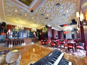 a restaurant with a piano and a bar with tables and chairs at Babylon Hotel in Dongguan