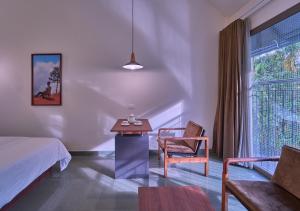 a bedroom with a bed and a table and a chair at Achutham Cottages Wayanad by VOYE HOMES - Nature Luxe near Banasura Dam in Padinjarathara