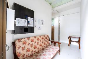 een bank in een kamer met een tv aan de muur bij XX Mitr Inn Sukhumvit 2 - มิตร อินน์ สุขุมวิท 2 in Bang Kapi