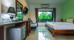 ein Schlafzimmer mit Bett, Schreibtisch und Fenster in der Unterkunft Tamali Hotel in Ban Yuan Lae