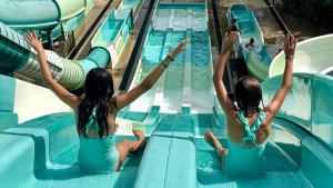 Tres chicas se deslizan por un tobogán de agua en una piscina. en La Vetta Village Vacances Camping, en Porto Vecchio