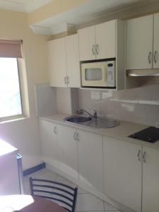 a white kitchen with a sink and a microwave at Bel Mondo Apartments in Wollongong