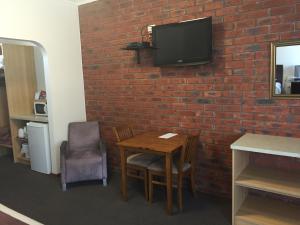 a room with a table and a tv on a brick wall at Ploughmans Motor Inn in Horsham