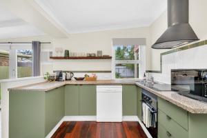 a kitchen with green and white cabinets and wood floors at Bassett Cottage- Heritage Listed- with 3 bedrooms- close to train and shops 