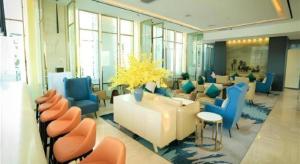 un hall d'entrée avec une salle d'attente avec des chaises bleues et oranges dans l'établissement Jinjiang Metropolo Hotel - Turpan Administration Center, à Turfan