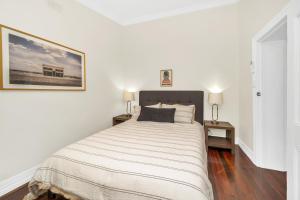 a white bedroom with a large bed and two lamps at Bassett Cottage- Heritage Listed- with 3 bedrooms- close to train and shops 