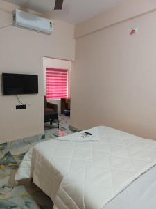Un dormitorio blanco con una cama y un televisor. en Radhika Residency, en Perintalmanna