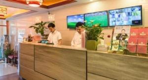 two men standing at a counter in a restaurant at GreenTree Inn Beijing Dongcheng District Wangfujin South Luogu Lane Houhai Express Hotel in Beijing