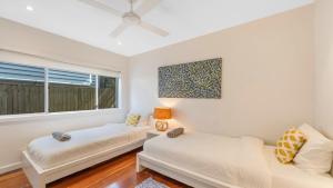 a living room with two beds and a window at 'Footsteps to the Bay' by HolidayCo in Pretty Beach