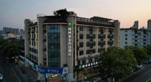 ein großes Gebäude mit einem Baum darüber in der Unterkunft GreenTree Inn Jiangsu Wuxi Xishan DongTing Erquan East Road XinGuang Newly Estate Express Hotel in Wuxi