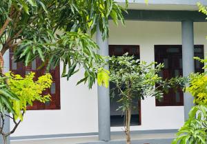 biały budynek z drzewami przed nim w obiekcie Vibra Hostel w mieście Sigirija