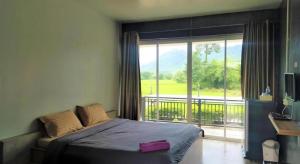 a bedroom with a bed and a window with a balcony at Loft Village in Ban Khlong Kathon