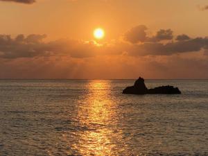 una puesta de sol sobre el océano con una roca en el agua en En- Hostel & Café bar, en Amami 13 fotos más