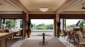 a living room with large windows and a table at La Résidence Phou Vao in Luang Prabang