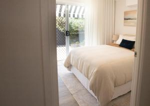 una camera da letto con un letto e una porta scorrevole in vetro di Coastal Courtyard Retreat Jasmine Hideaway Sunshine Coast a Kawana Waters