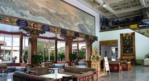 a lobby with tables and chairs and a large painting on the wall at Lhasa Hotel in Lhasa