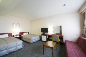 um quarto de hotel com duas camas, uma secretária e um sofá em Ise City Hotel em Ise