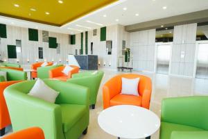 - un hall avec des chaises vertes et orange et une table dans l'établissement My Tower Hotel Surabaya, à Surabaya