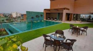 a swimming pool with tables and chairs on a building at Hotel Castle Salam in Khulna
