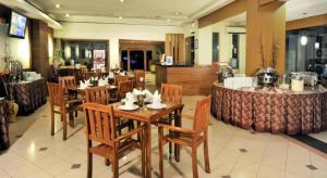 a restaurant with wooden tables and chairs and a bar at Muria Hotel in Semarang