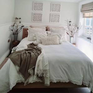 una habitación con una cama grande con sábanas y almohadas blancas en R&R Roo & Rest, en Singleton