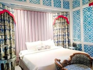 a bedroom with a white bed and a chair at Kamiseta Hotel in Camp John Hay