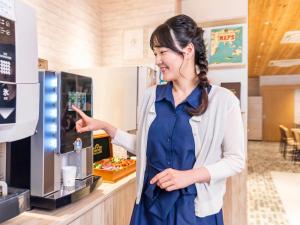 a woman standing in front of a coffee machine at Comfort Hotel Toyama in Toyama