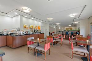 ein Restaurant mit Tischen und Stühlen und einer Theke in der Unterkunft Comfort Inn & Suites Covington - Mandeville in Covington