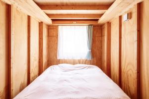 a bed in a wooden room with a window at MOBILITA COURT IWATE in Hachimantai