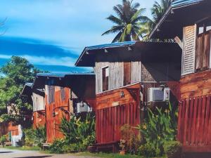 une rangée de maisons en bois avec un palmier en arrière-plan dans l'établissement Jidapa Resort, à Ban Khlong Takhian