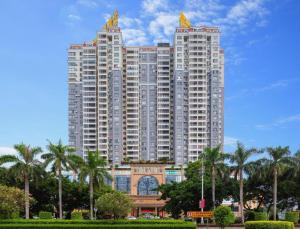 a tall building with palm trees in front of it at Manhatton Hotel Beihai in Dianbailiao