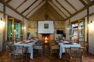 a dining room with tables and chairs and a fireplace at Chiangkham Luang Resort in Ban Huai Sai