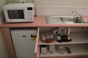 una pequeña cocina con fregadero y microondas en Central Coast Motel, en Wyong