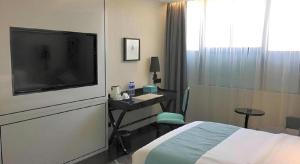 una camera d'albergo con un letto, una scrivania e una televisione di Xana Hotelle XiAn Gig Wild Goose Pagoda Branch a Xi'an