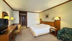 雅加达HERITAGE by Grand Sahid Jaya的一间配有床和电视的酒店房间