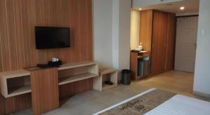 ein Wohnzimmer mit einem TV an einer Holzwand in der Unterkunft Grand Dian Hotel Slawi in Procot