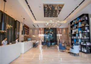 un hall d'une bibliothèque avec une femme assise au comptoir dans l'établissement Echarm Hotel Danzhou Xiari Plaza, à Danzhou