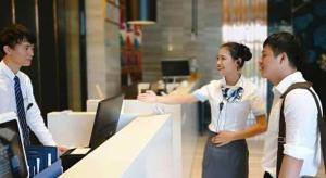 un homme et une femme debout devant un comptoir dans l'établissement Echarm Hotel Danzhou Xiari Plaza, à Danzhou